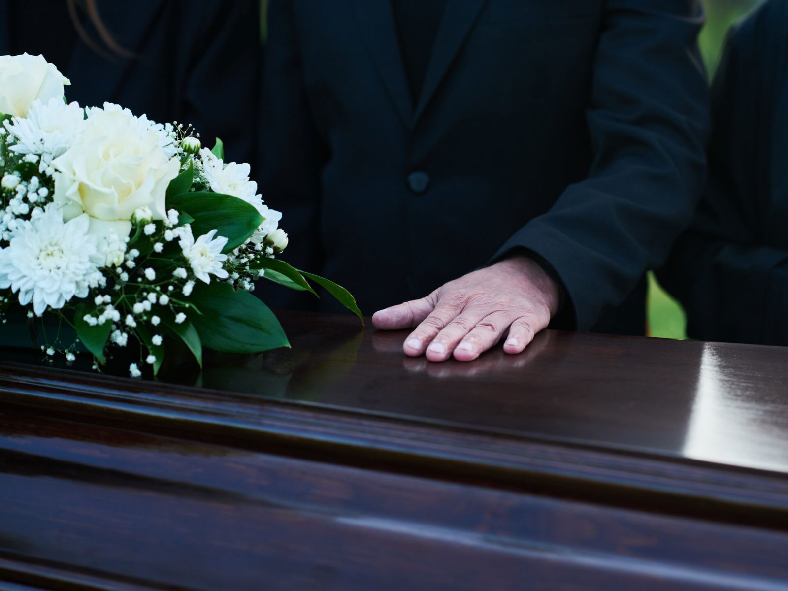 Man places hand on coffin